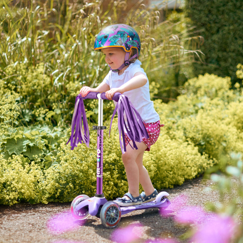 Small child riding a purple micro scooter