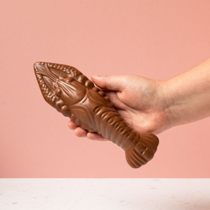 Hand holding an unwrapped Chcoco milk chocolate lobster