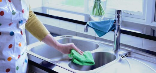 person stood by a sink with greener cleaner cloth
