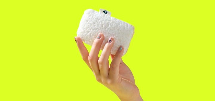 A hand holding up a Seep sponge scourer