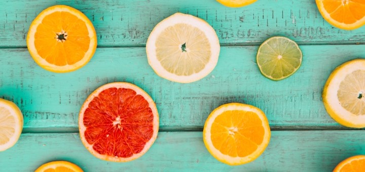 Slices of oranges, limes and lemons on a blue table top.