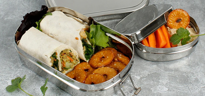 A Slice of Green oval filled lunchbox open on a table