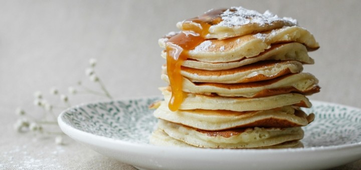 A stack of pancakes on a light coloured plate against a white background