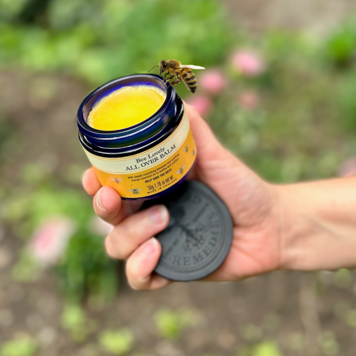 A hand holding a jar of Neals Yard Remedies all over balm
