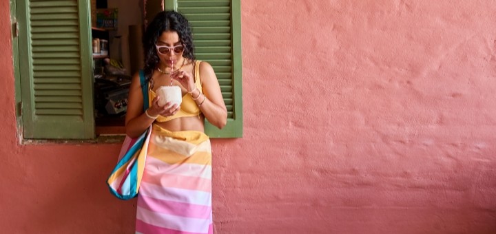 A women wrapped in a Dock & Bay towel against a pink wall
