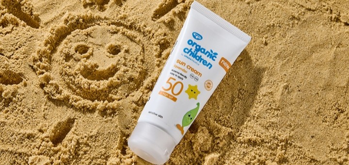 A tube of Green People kids suncream on some sand